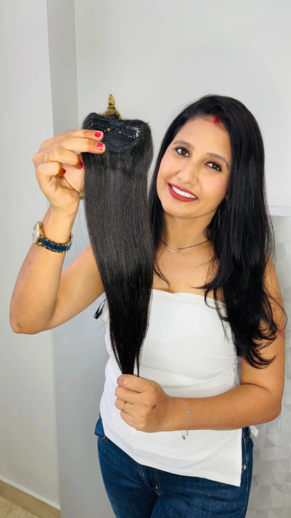 Smiling woman holding black straight hair extension clip in modern indoor setting