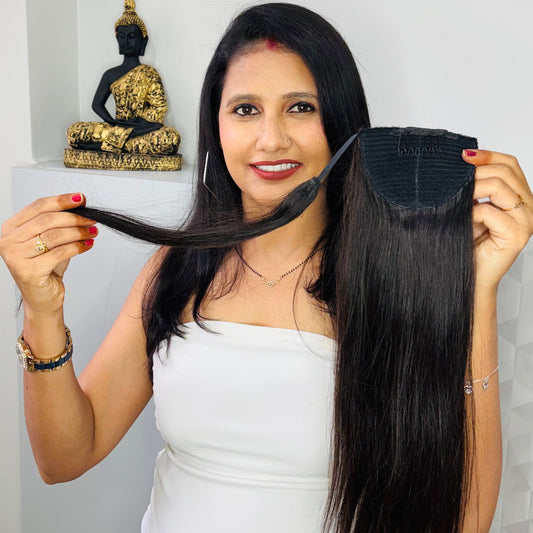 Woman holding a hair extension with a white wall and Buddha statue in the background